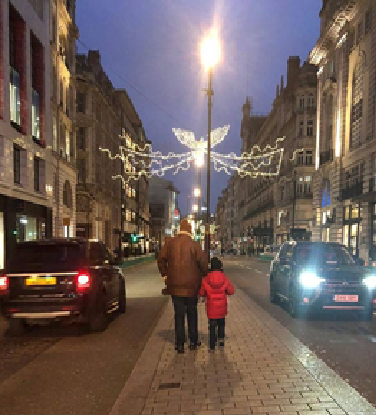 Father and child doing a London Winter walk below the Christmas lights.